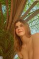 A woman in a bikini posing in front of a palm tree.