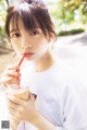 A woman holding a cup of coffee with a straw in it.