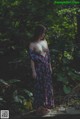 A woman in a long dress standing in the woods.