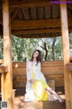 A woman in a yellow dress sitting on a wooden bench.