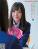 A young woman in a school uniform sitting at a desk.