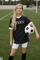 A young woman holding a soccer ball on a soccer field.