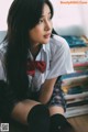 A woman in a school uniform sitting on the floor.