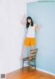 A woman standing on top of a wooden chair.