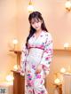 A woman in a white kimono standing in a room.